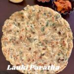 A flat, round, cooked lauki paratha (bottle gourd flatbread) is centered on a dark surface. The paratha has visible pieces of shredded lauki and green herbs. In the top right corner, small bowls contain a red chutney and a dark orange pickle. A lemon wedge is in the top left corner. The text "Lauki Paratha" is overlaid in white at the bottom of the image.