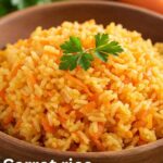 Carrot Rice Recipe: A close-up shot of a wooden bowl filled with bright orange carrot rice, garnished with a sprig of parsley. The rice is fluffy and flecked with grated carrots, and the URL "taazarecipes.com" is visible in the bottom right corner.