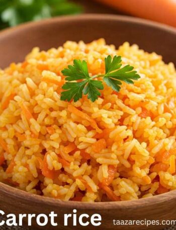 Carrot Rice Recipe: A close-up shot of a wooden bowl filled with bright orange carrot rice, garnished with a sprig of parsley. The rice is fluffy and flecked with grated carrots, and the URL "taazarecipes.com" is visible in the bottom right corner.