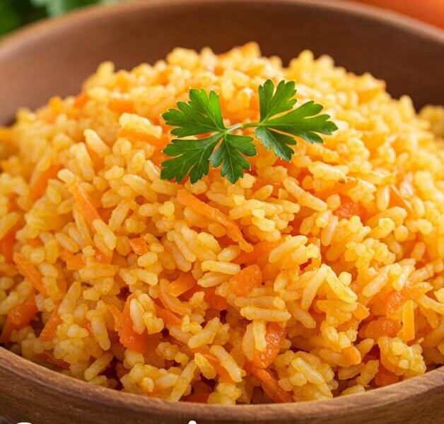 Carrot Rice Recipe: A close-up shot of a wooden bowl filled with bright orange carrot rice, garnished with a sprig of parsley. The rice is fluffy and flecked with grated carrots, and the URL "taazarecipes.com" is visible in the bottom right corner.