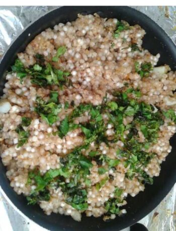 Sabudana Khichdi Recipe in a black pan, garnished with fresh cilantro.